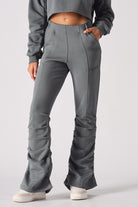 Detailed view of the flared hem and ruched stitching on grey joggers