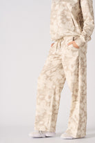 Model posing in a relaxed stance wearing beige tie dye wide leg joggers