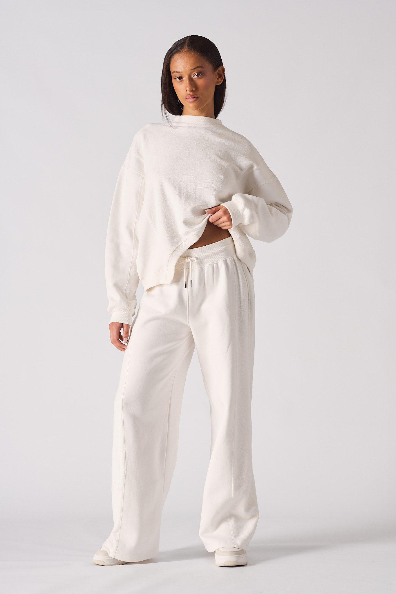Full length view of model wearing a white crew neck jumper womens with matching trousers