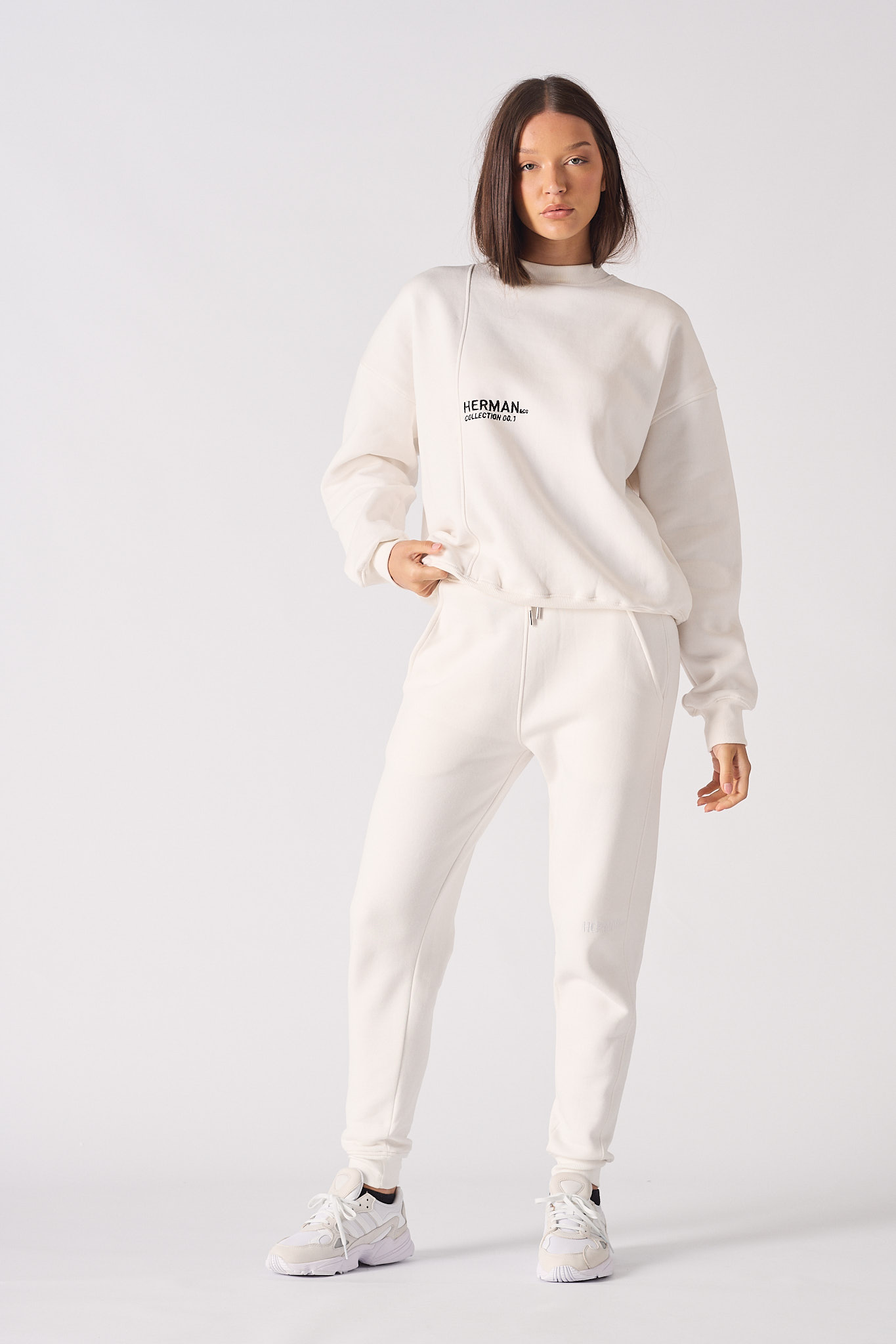 Front view of model wearing white crewneck sweatshirt women's with black chest logo