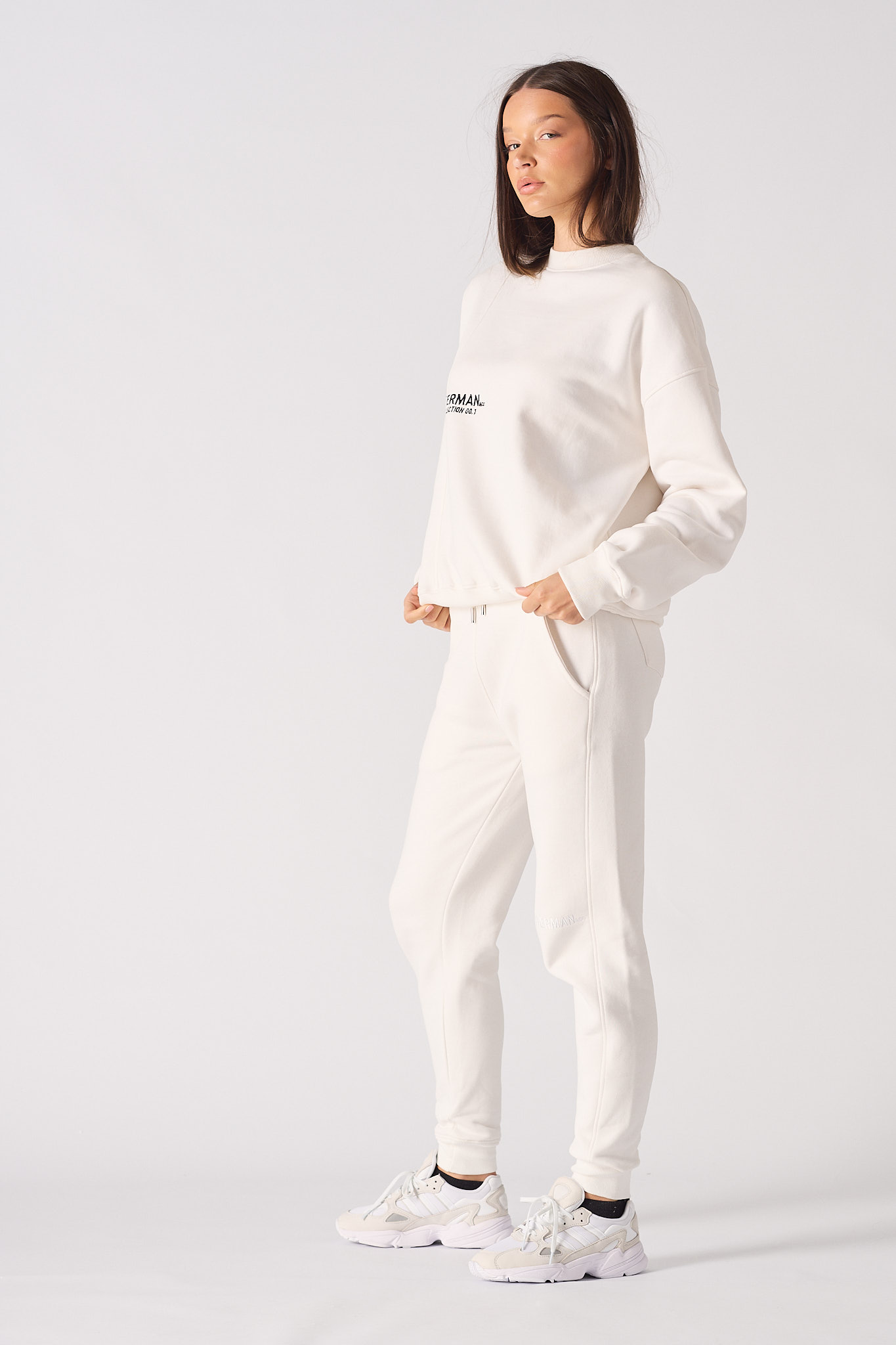 Side profile view showing the relaxed fit of the women's white crewneck jumper