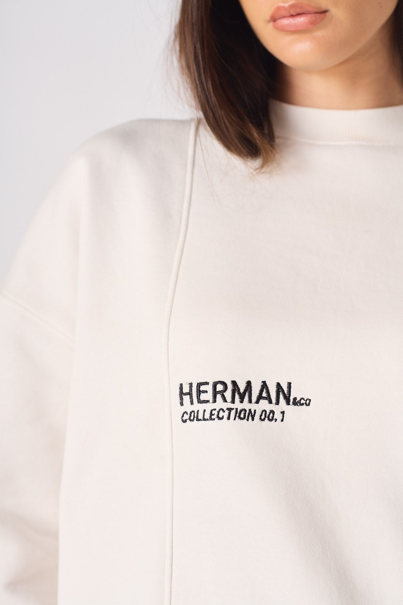 Detailed view of the ribbed sleeve cuff on the white crewneck sweatshirt