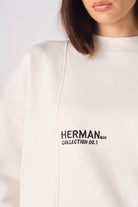 Detailed view of the ribbed sleeve cuff on the white crewneck sweatshirt