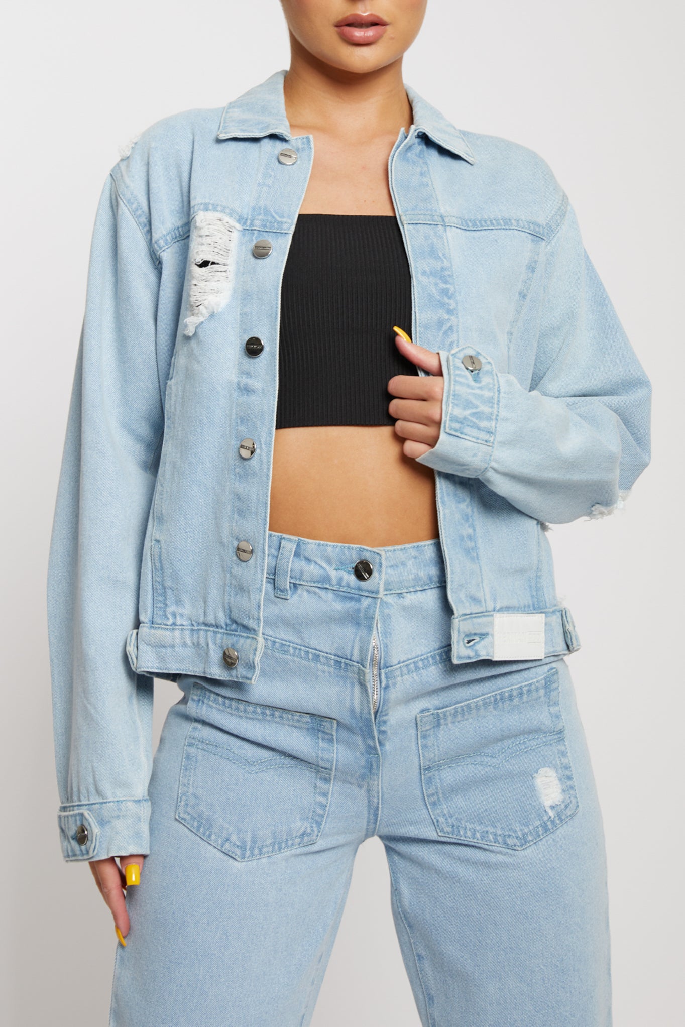 Close-up of the women's light wash distressed jacket showing the rip details.