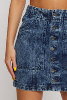 Detailed close-up of the pocket and branded buttons on the acid wash denim skirt
