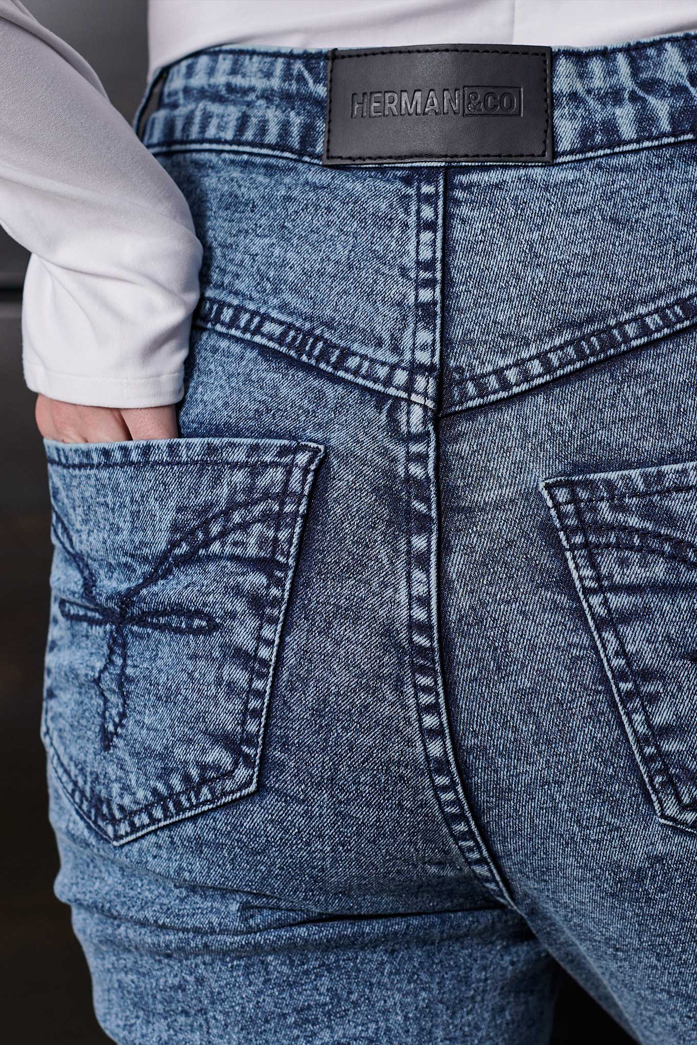 Close-up of the embroidered back pocket detail on the acid wash jeans