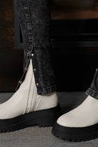 Detailed view of the split hem with poppers on the acid wash jeans over boots