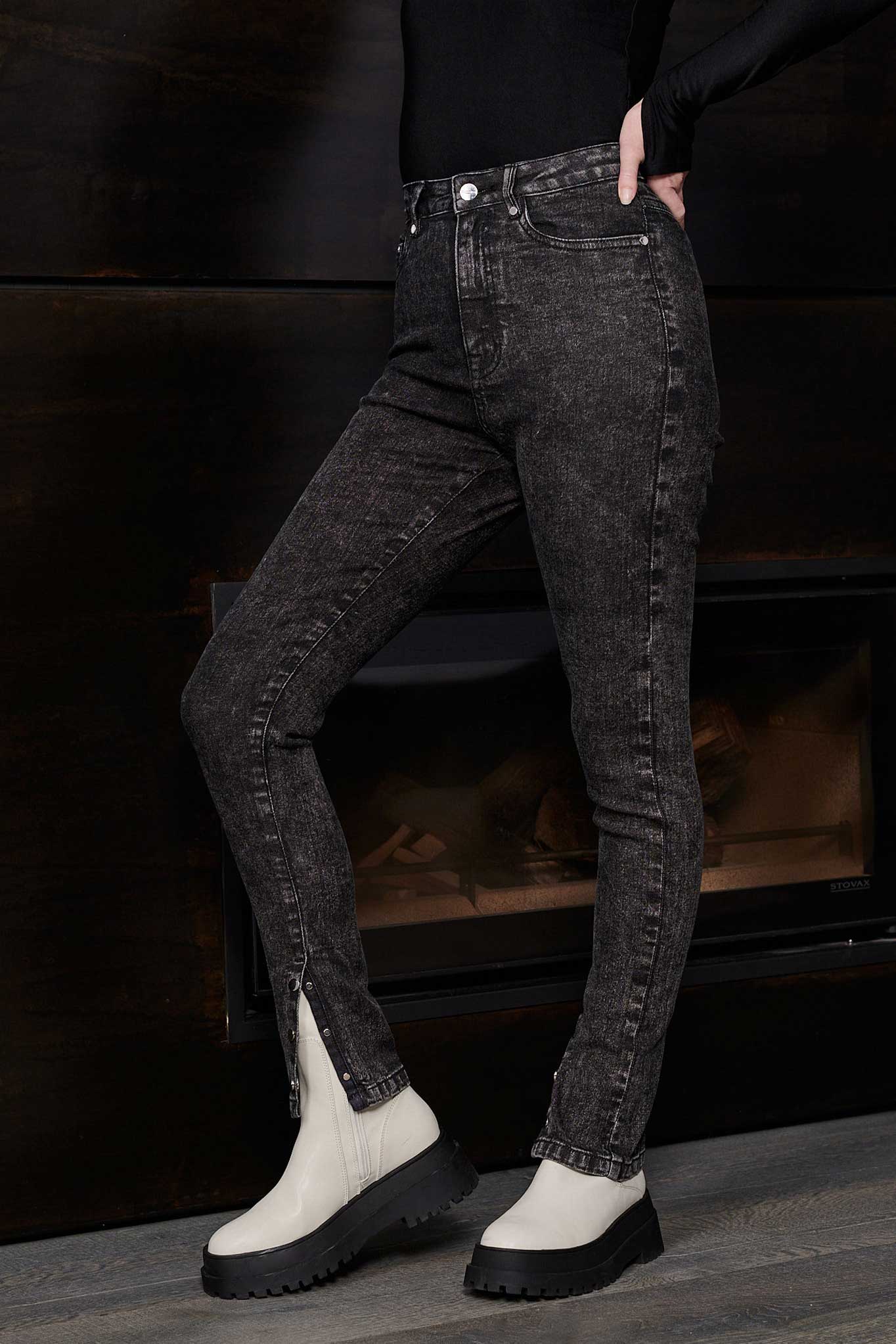 Side view of a model wearing acid wash skinny jeans with the popper hem open