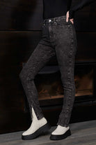 Side view of a model wearing acid wash skinny jeans with the popper hem open