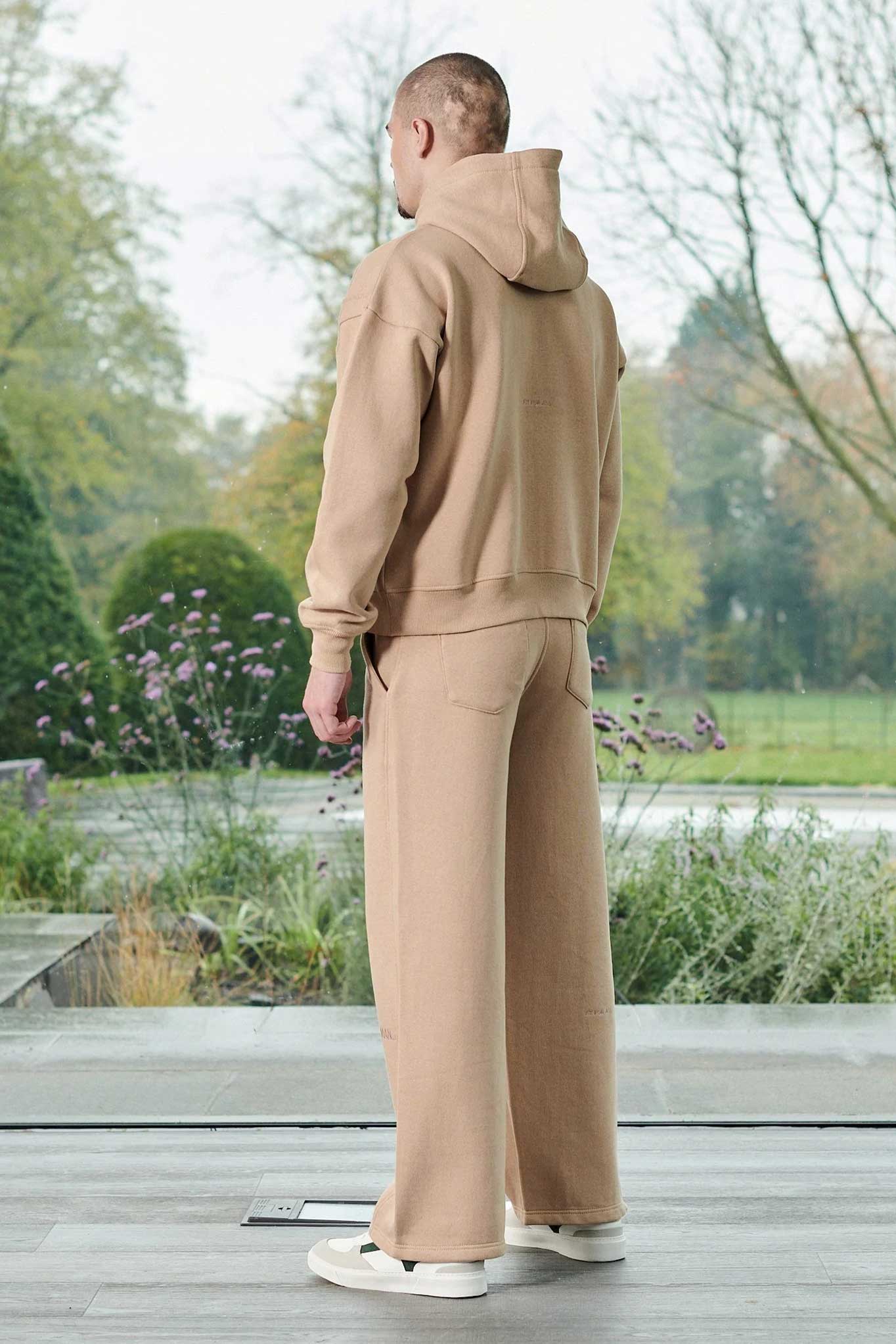 Rear view of men wearing a relaxed fit beige hoodie showing the back design