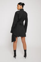 Back view of a model in the black cotton asymmetric shirt dress.