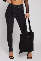 A model holding the black denim tote bag with black skinny jeans.\