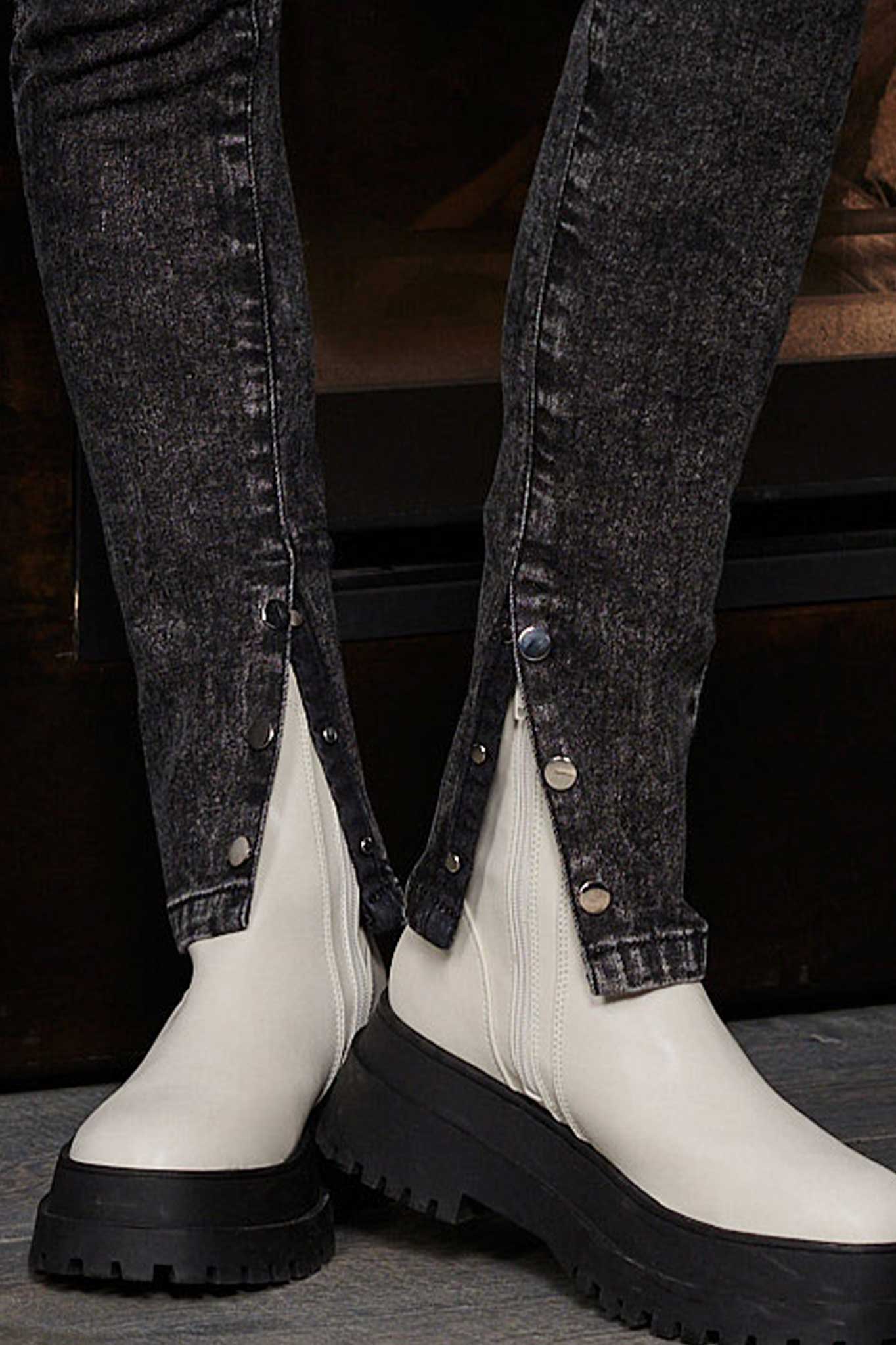 Close-up detail of the silver popper buttons on the ankle of the black jeans