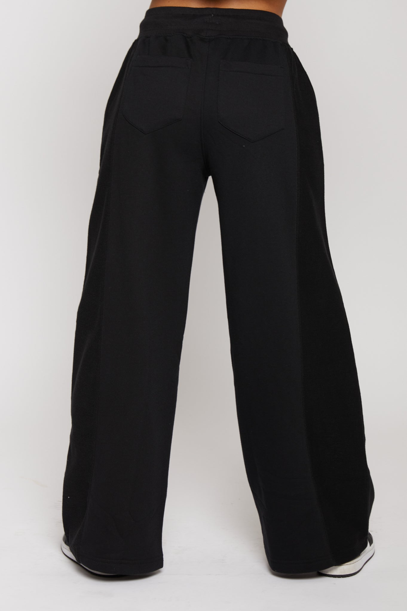 Rear view of model standing in black kroen joggers womens showing the back pocket fit