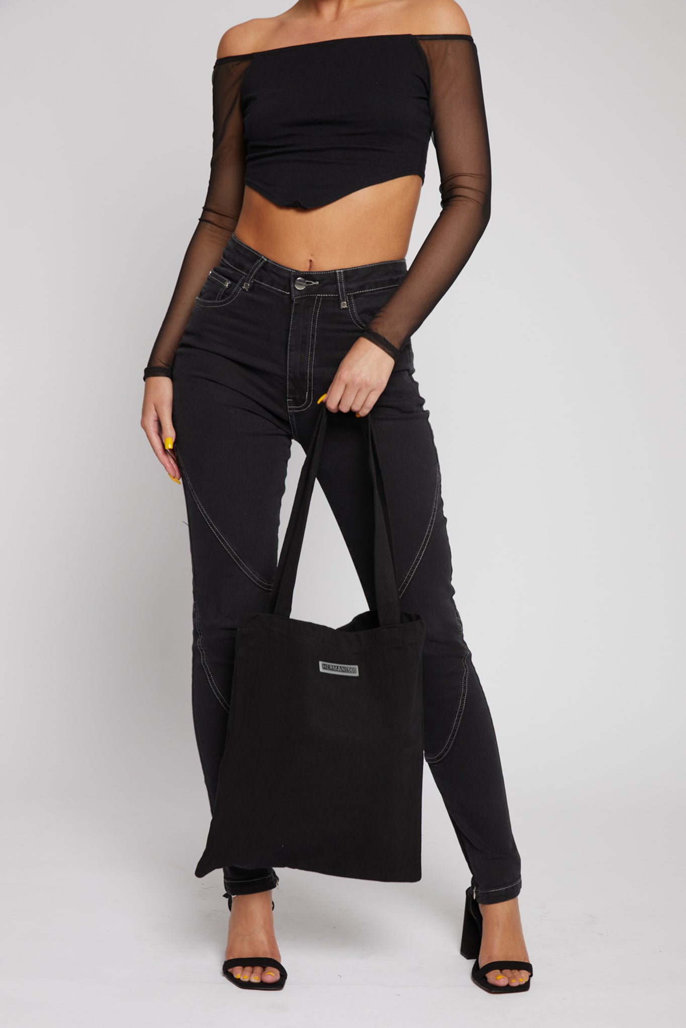 A model styled with the black wash denim tote bag and an all-black outfit.