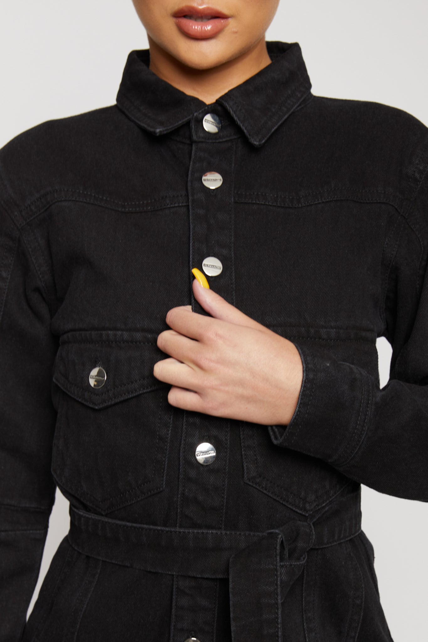 Detailed close-up of the silver branded buttons on the black washed denim dress