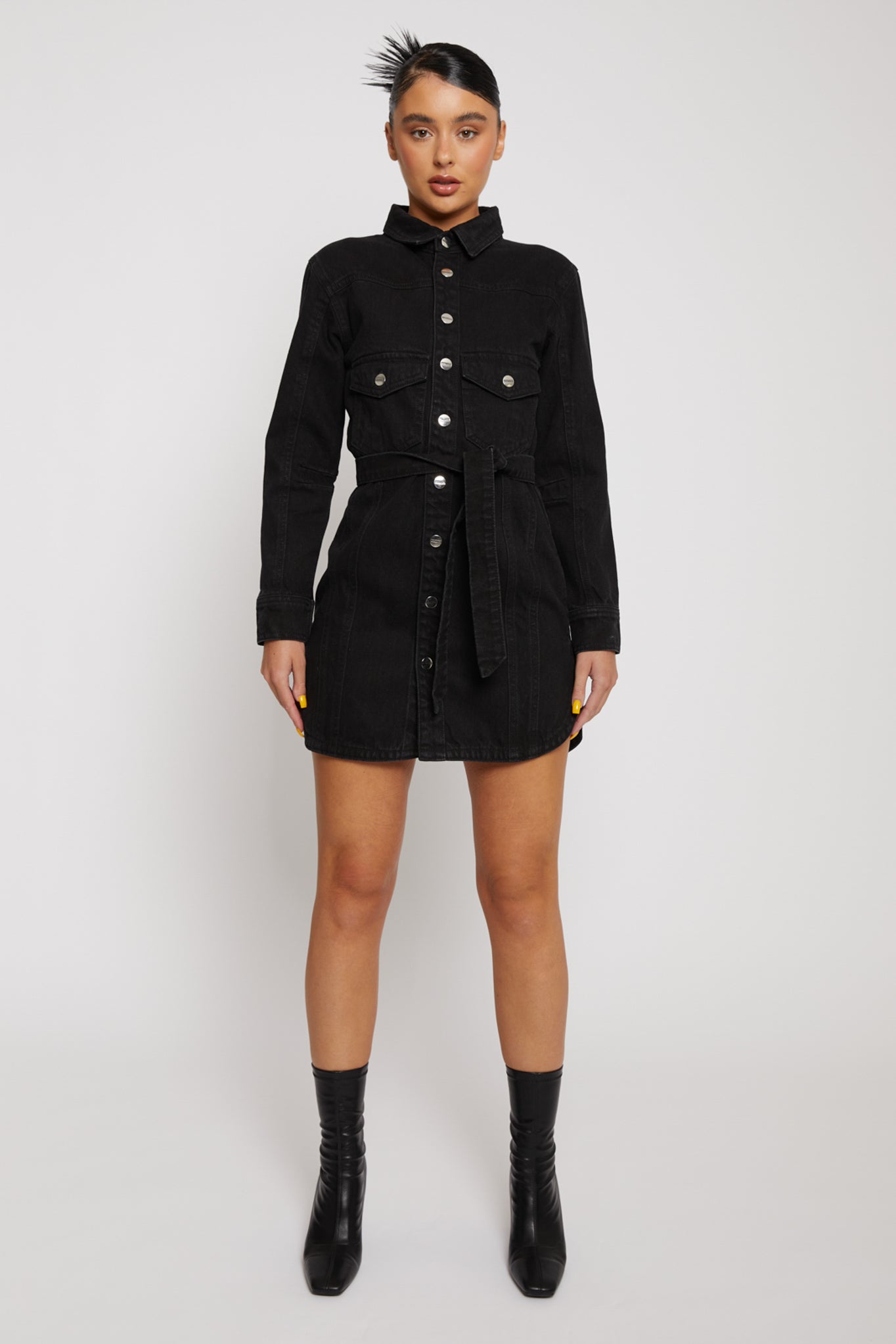 Front view of a model wearing the women's black washed denim dress with a tie belt