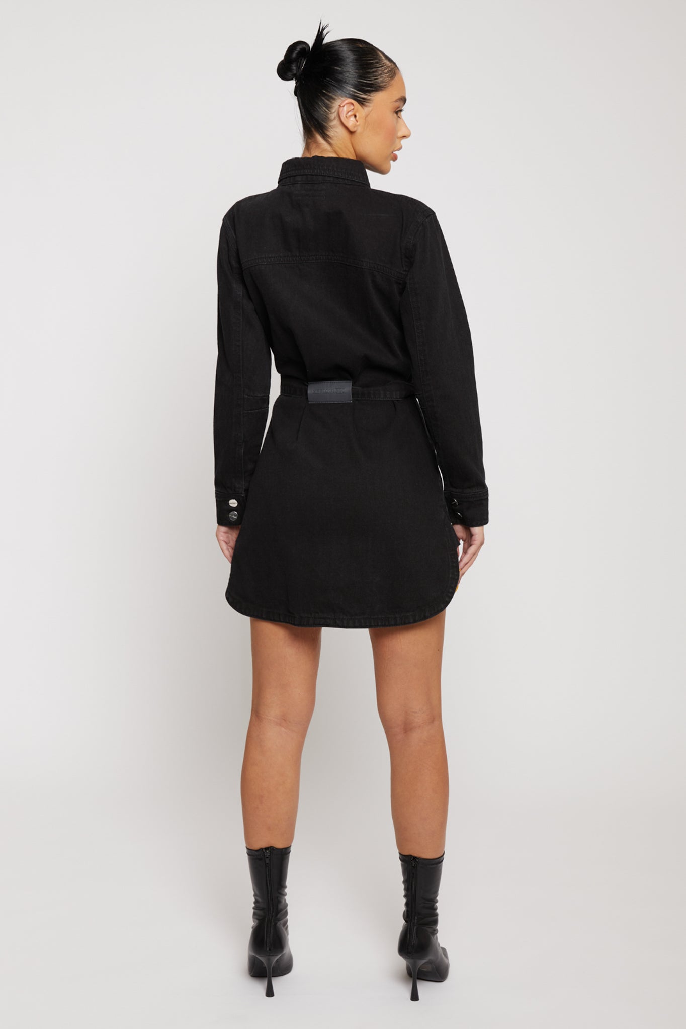 Back view of a model in the black washed jean dress with a belt