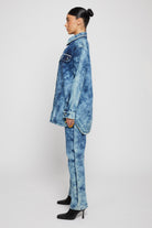 Side profile of a model showing the length of the bleach wash denim shirt.