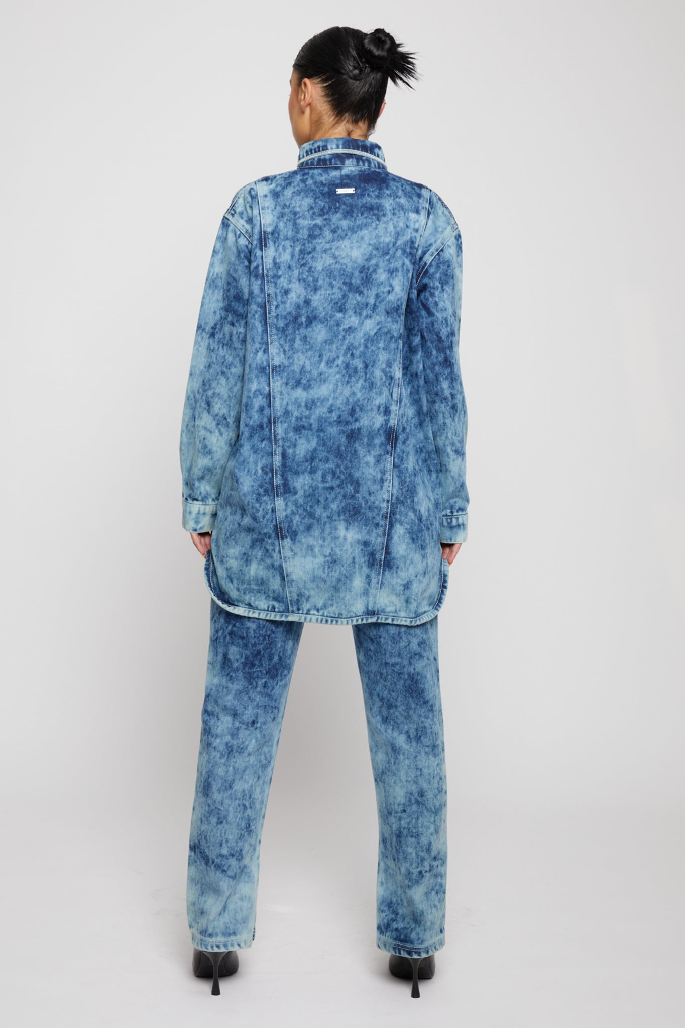 Back view of a model in the women's bleach wash denim shirt and matching jeans.