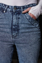 Close-up of the unique front pocket design on the blue acid wash jeans