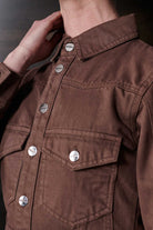 Close-up of the silver branded buttons and chest pocket on the brown denim dress