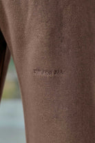 Close-up of the tonal 'Fit For All' embroidery on the brown joggers