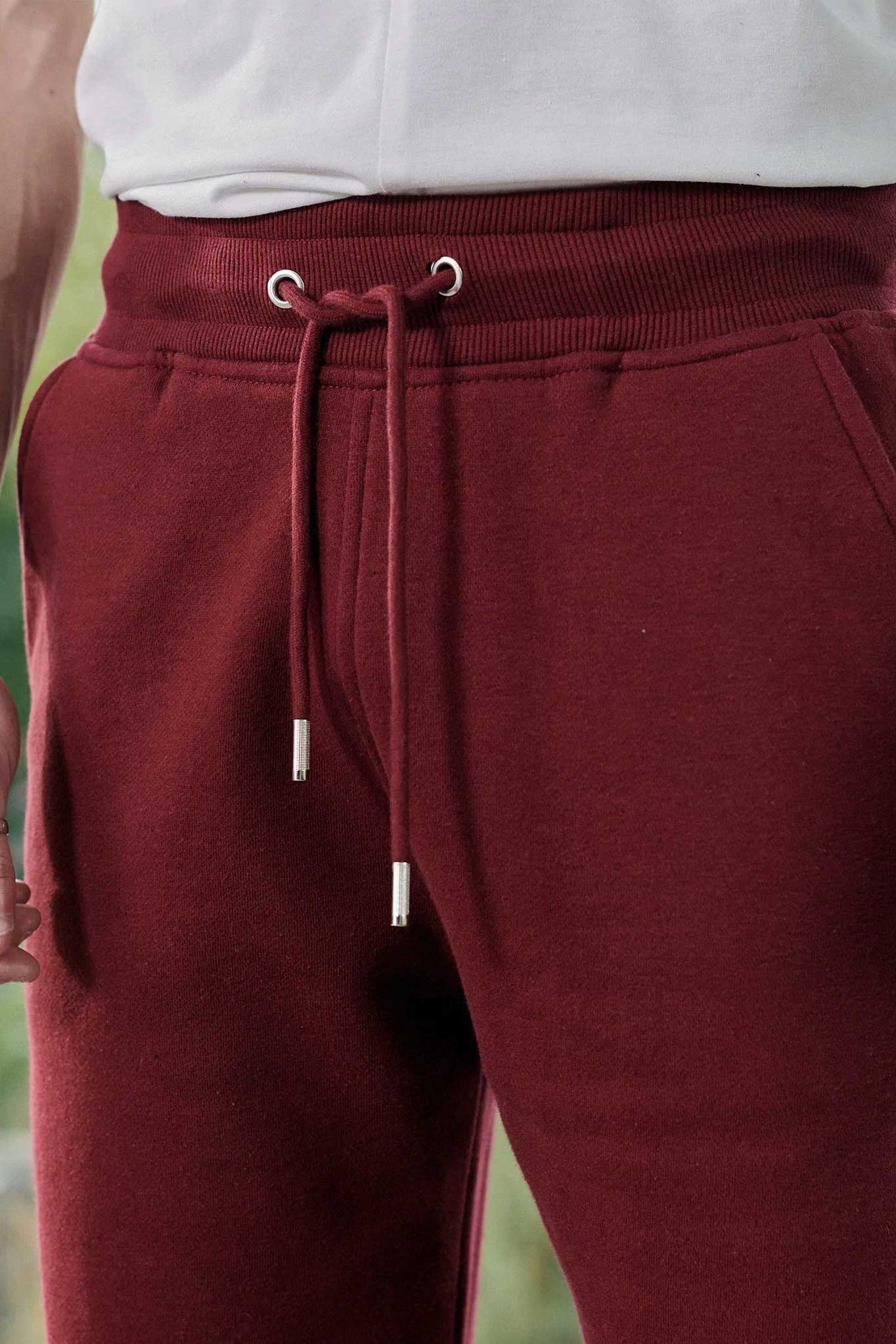 Close-up of the drawstring waist with silver toggles on the dark red tapered joggers.