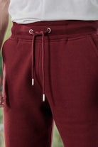 Close-up of the drawstring waist with silver toggles on the dark red tapered joggers.