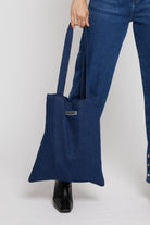 Close-up of the dark wash denim tote bag showing the fabric and logo.