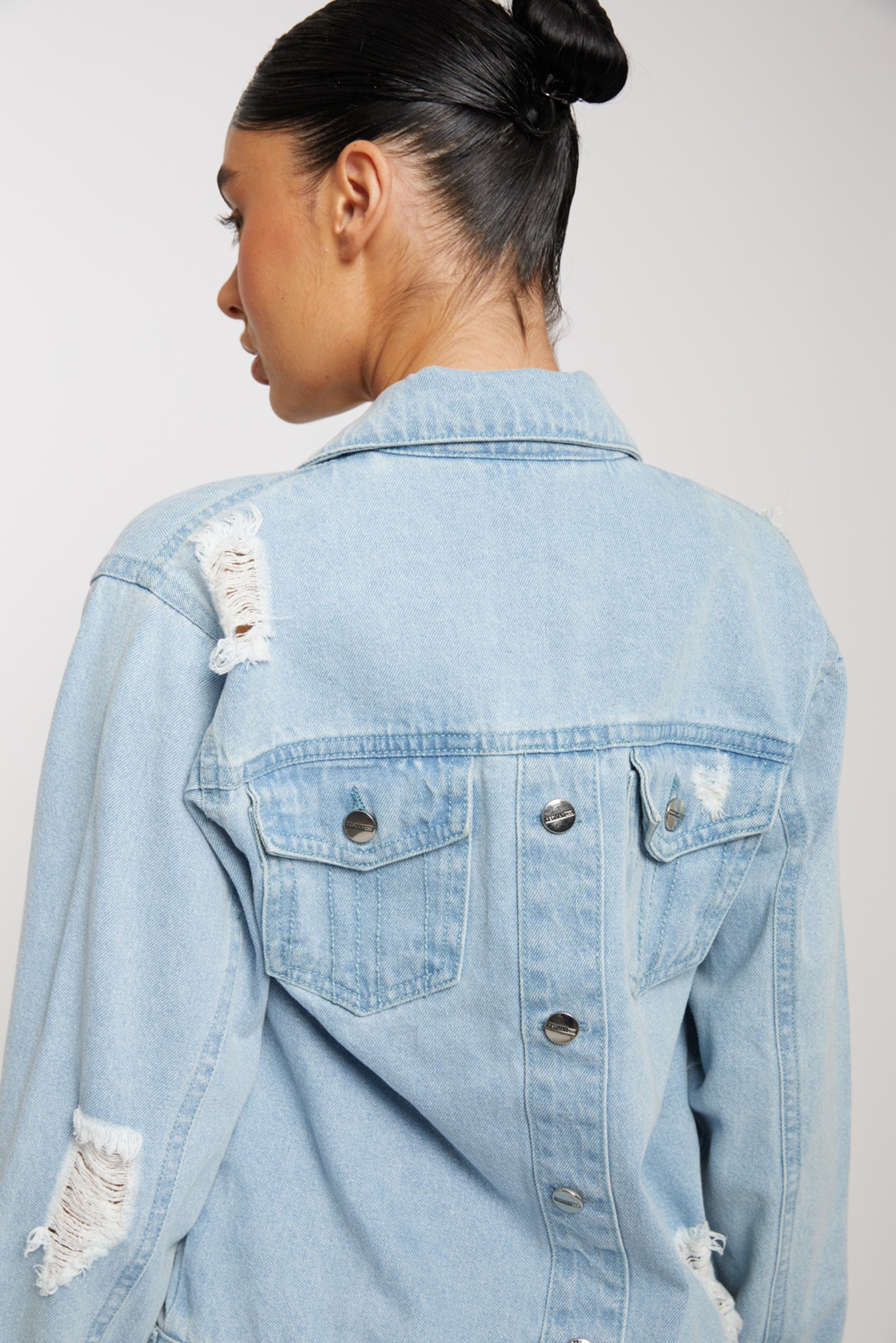 Close-up of the back showing the distressed details on the light wash denim jacket.