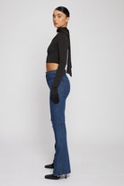 Side profile of a model showing the fit of the dark wash distressed flare jeans.