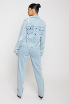 Back view of a model in the distressed light wash denim jacket showing button details.