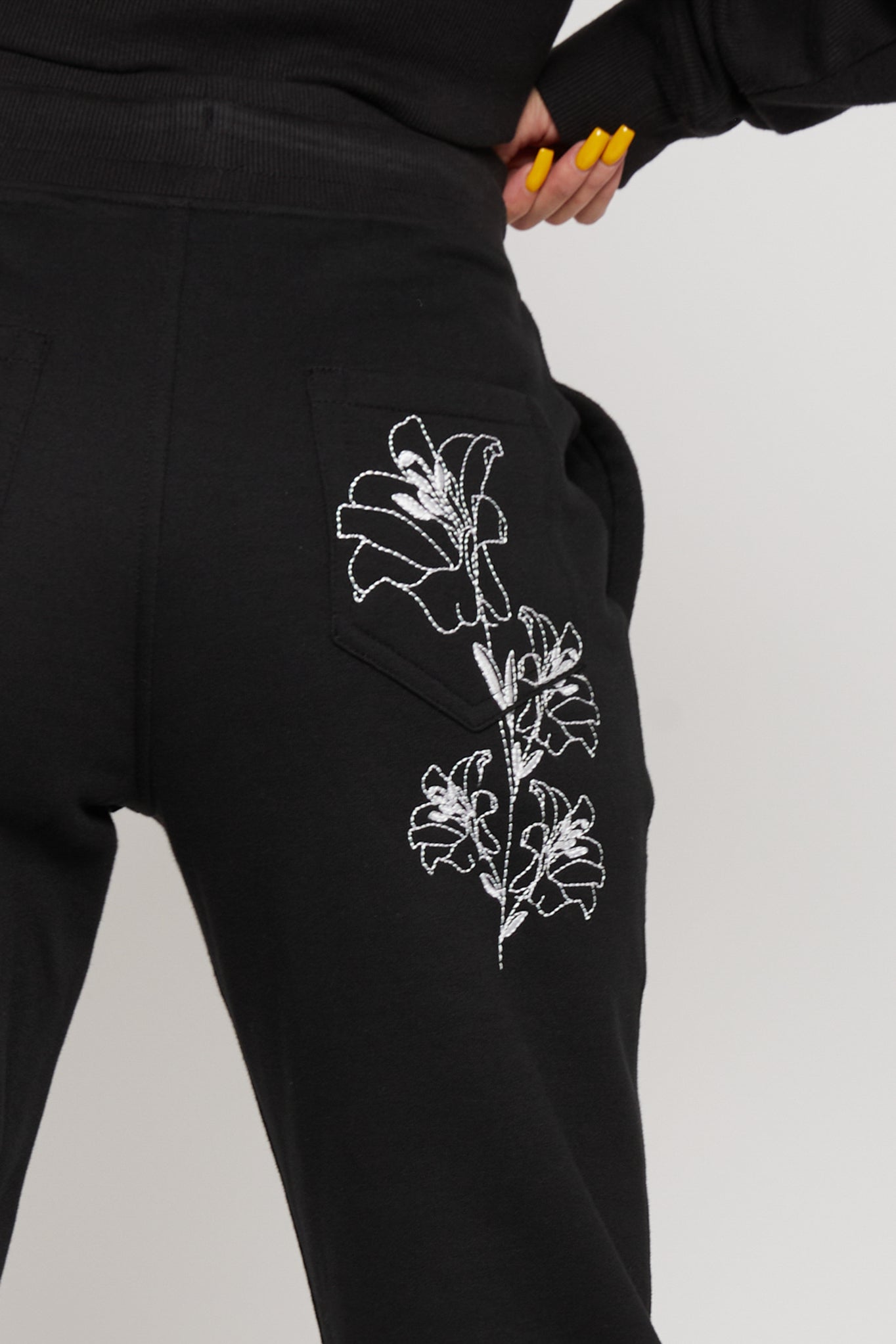 Close-up of the delicate white floral embroidery on the back pocket of the joggers
