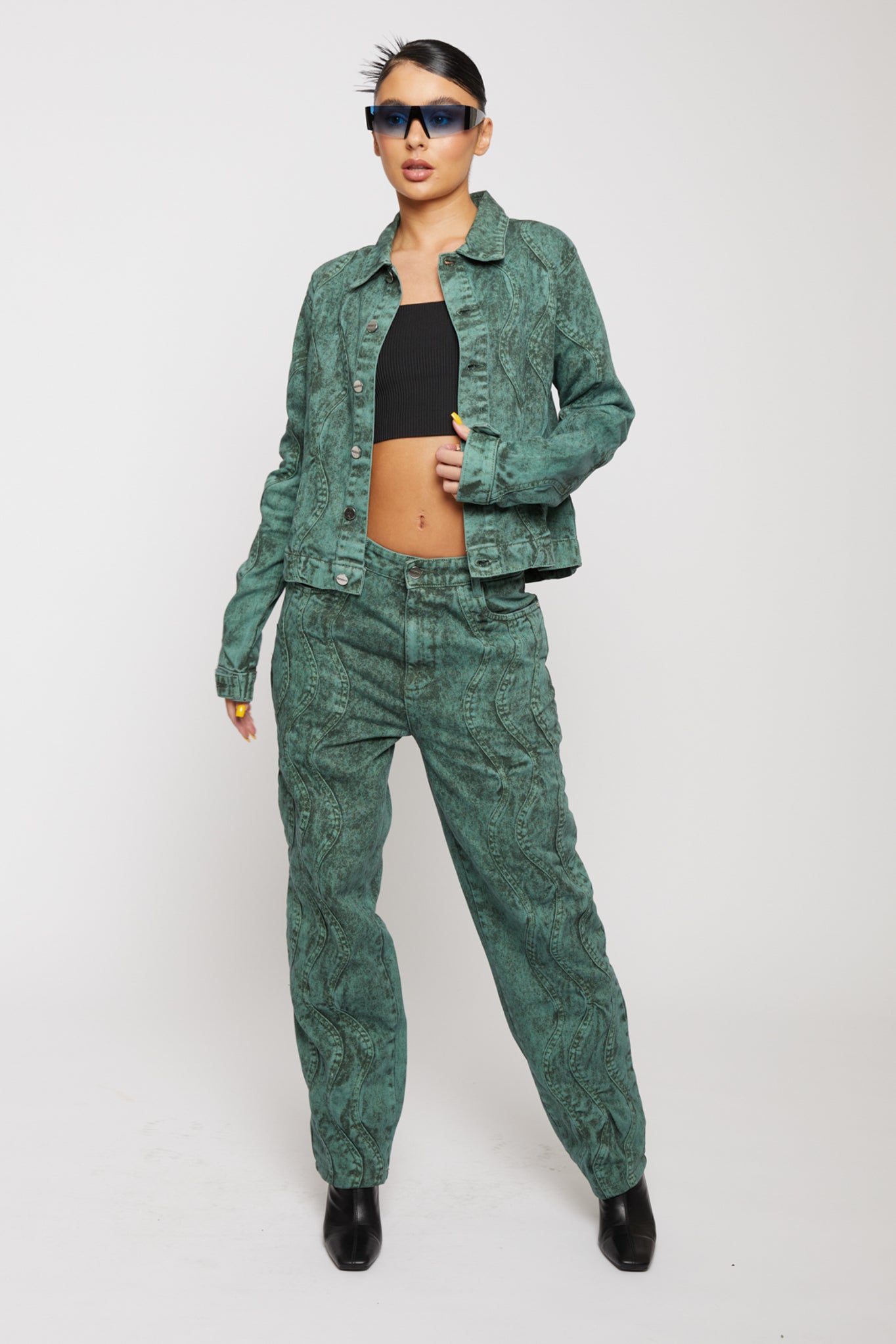 A model posing in the complete green acid wash denim outfit.