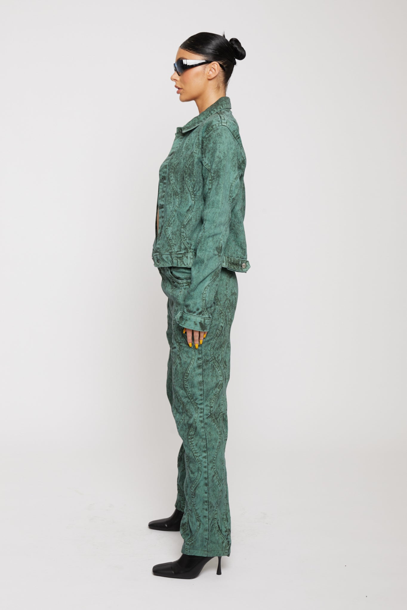 Side profile of a model in the green denim jacket and matching trousers