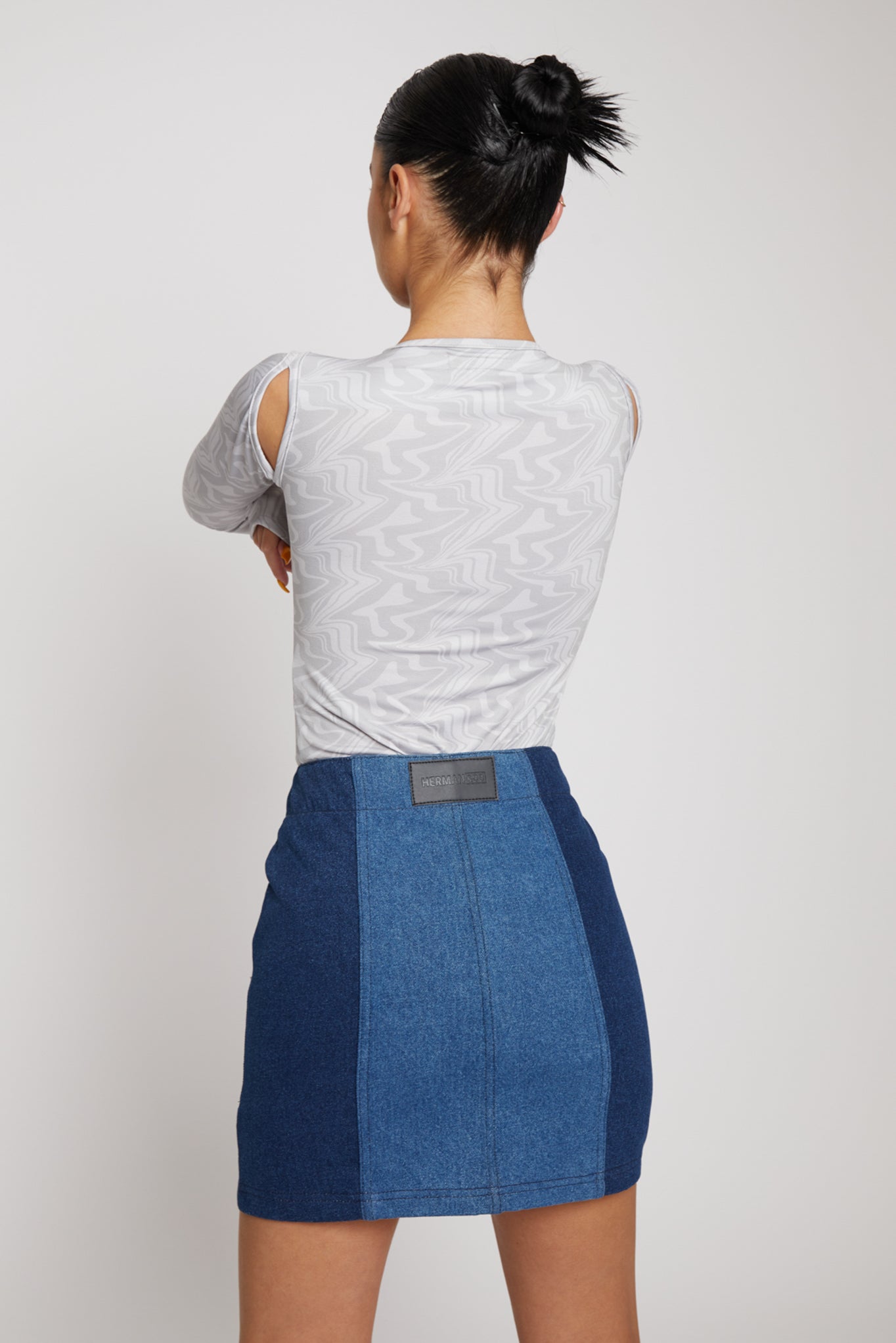 Back view of a model wearing the grey abstract print bodysuit with a denim skirt.