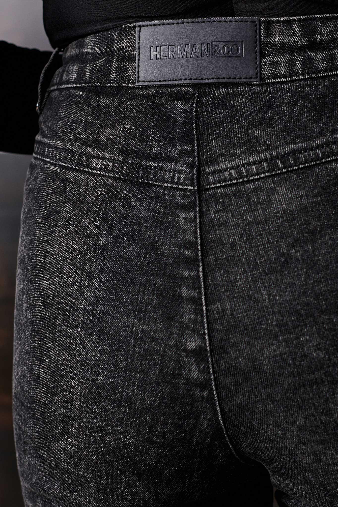 Close-up of the black Herman & Co logo patch on the back of the jeans