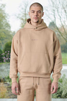 Close up detail of the tonal logo embroidery on the chest of mens beige hoodie