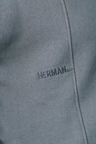 Close up detail of HERMAN text embroidery on grey jumper chest