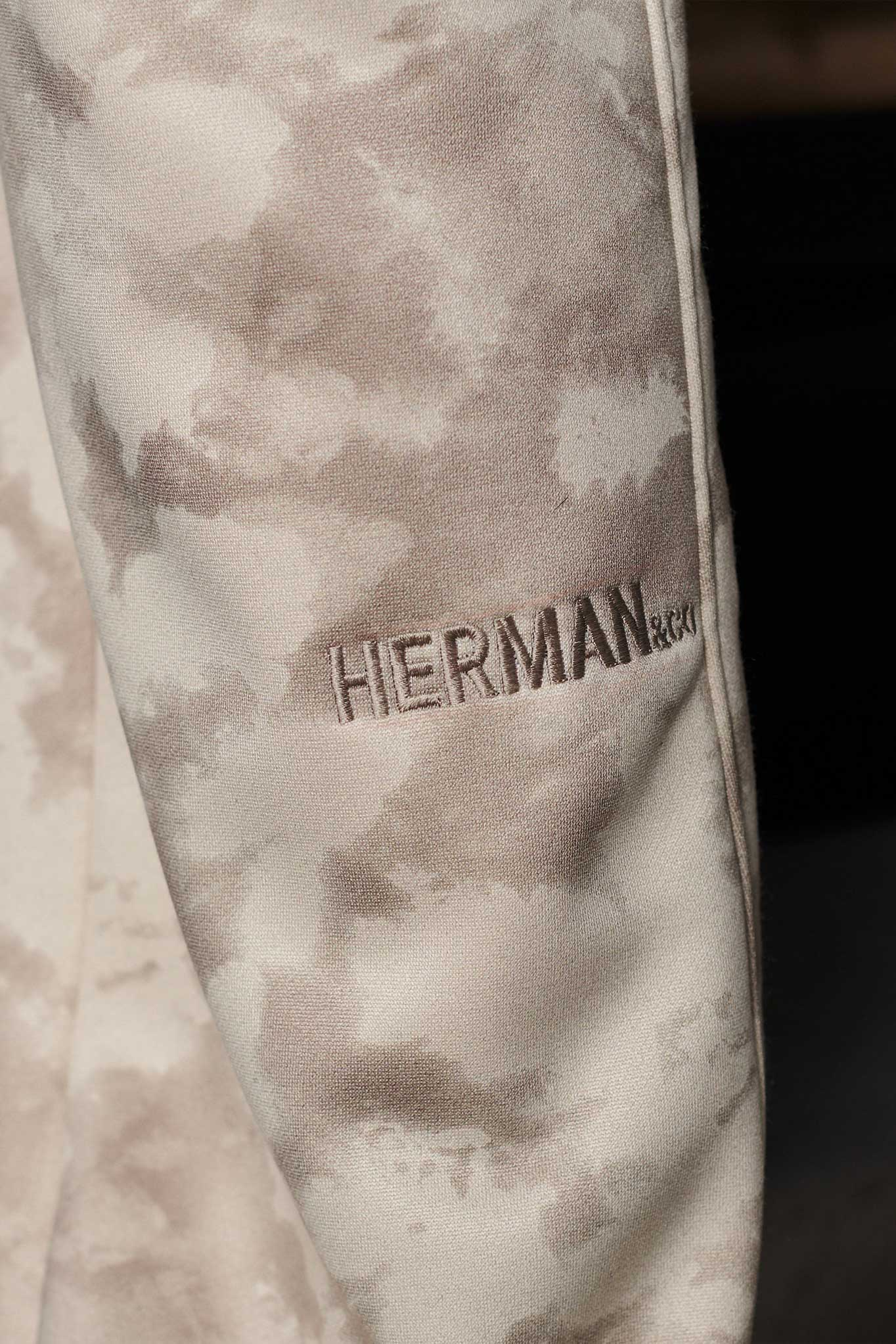Detail of Herman logo embroidery on the sleeve of mens tie dye hoodie