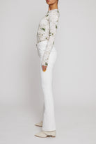 Side profile showing the fit of the high-waisted flare jeans in white.