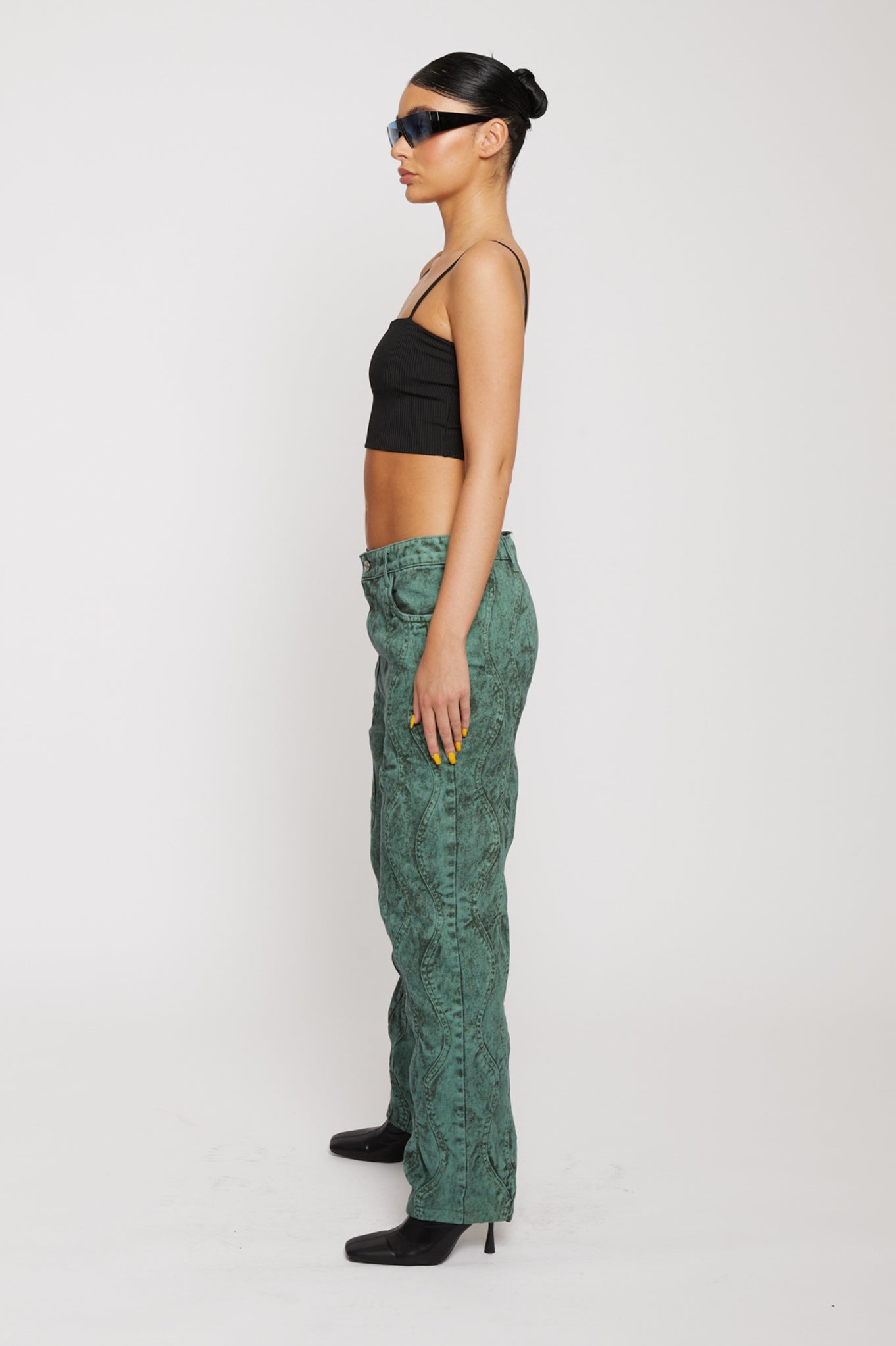 Side profile of a model wearing high-waisted green baggy jeans.