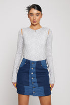 Front view of a model in the light grey cut-out shoulder bodysuit.