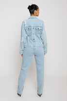 Full back view of a model in the light wash denim jacket and jeans set.