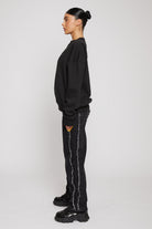 Side profile view showing the relaxed fit of the black crewneck sweatshirt for women
