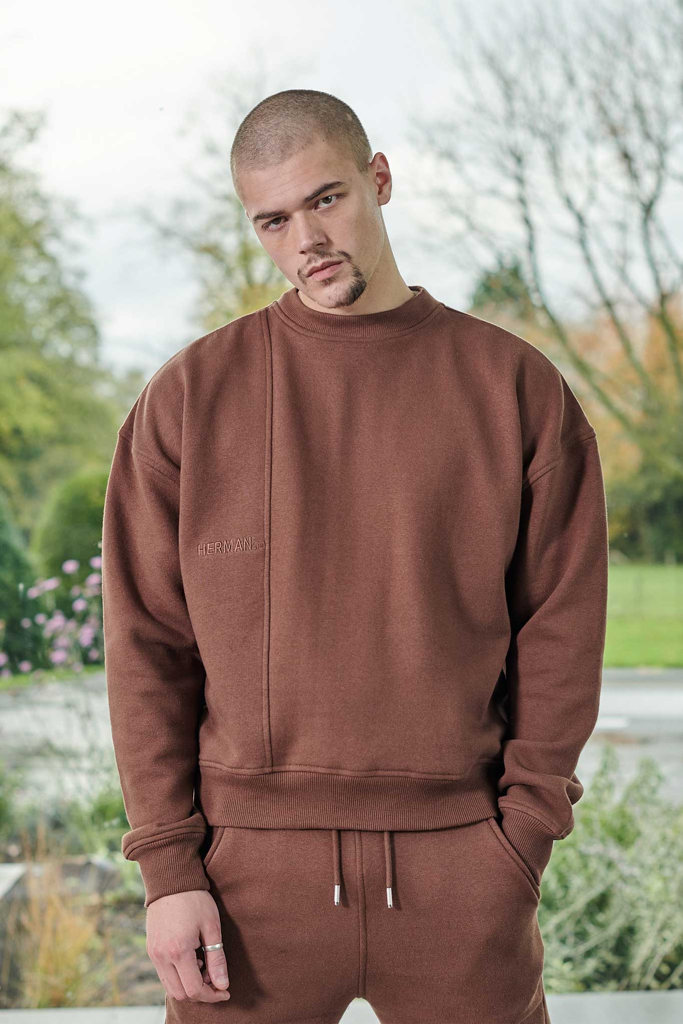 Close-up of a model wearing the oversized men's brown crew neck jumper.