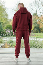 Back view of a model in the men's dark red jogger and matching hoodie set.