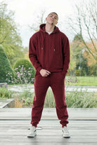 Full view of a model in the men's maroon zip-up hoodie and matching joggers