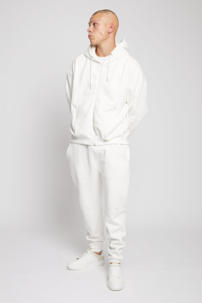 A model wearing the full men's white tracksuit with tapered joggers.